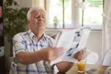 senior si odťahuje noviny, aby ich vedel prečítať
